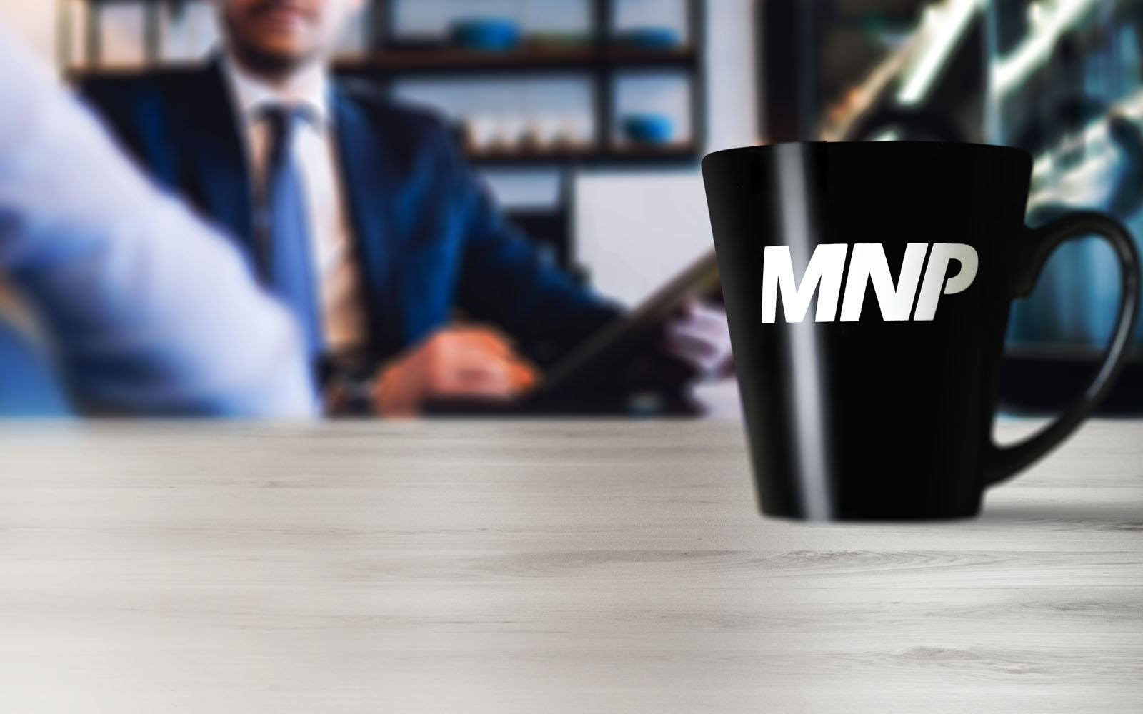 Tasse à café avec le logo MNP dessus, sur une table avec des gens d'affaires en arrière-plan