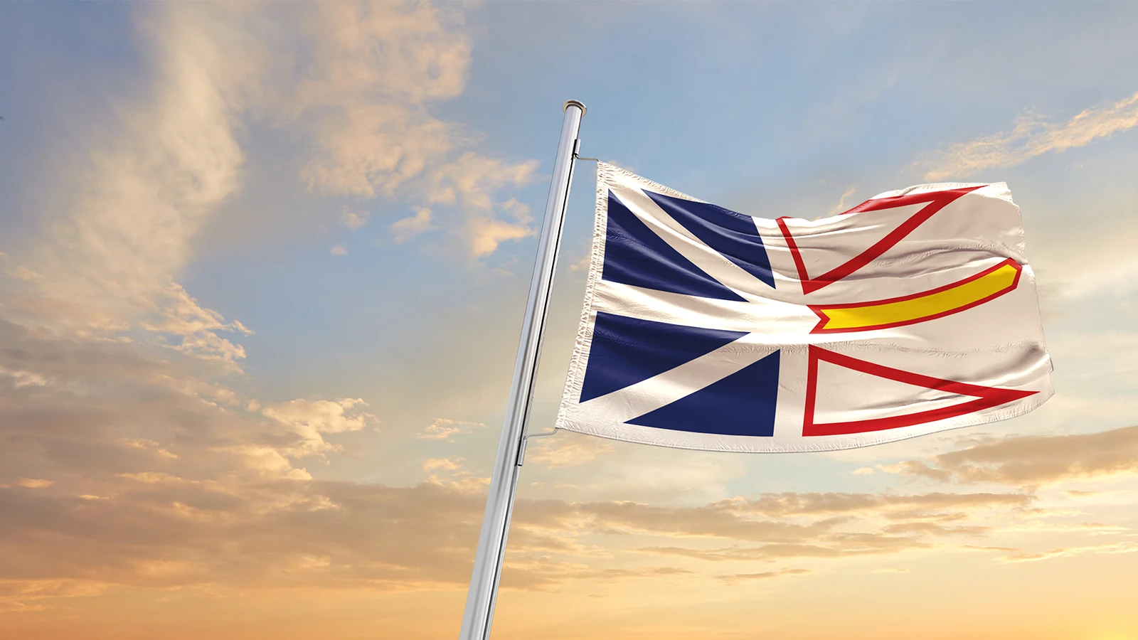 Newfoundland and Labrador flag blowing in wind with sunset backdrop