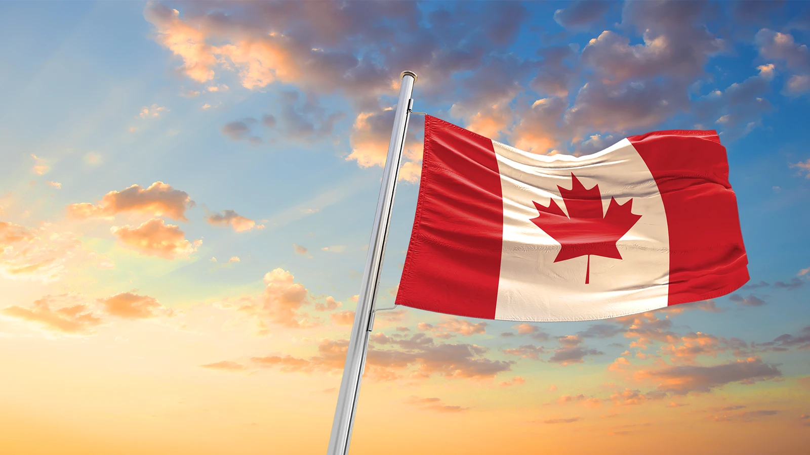 Canadian flag flying high above a blue sky