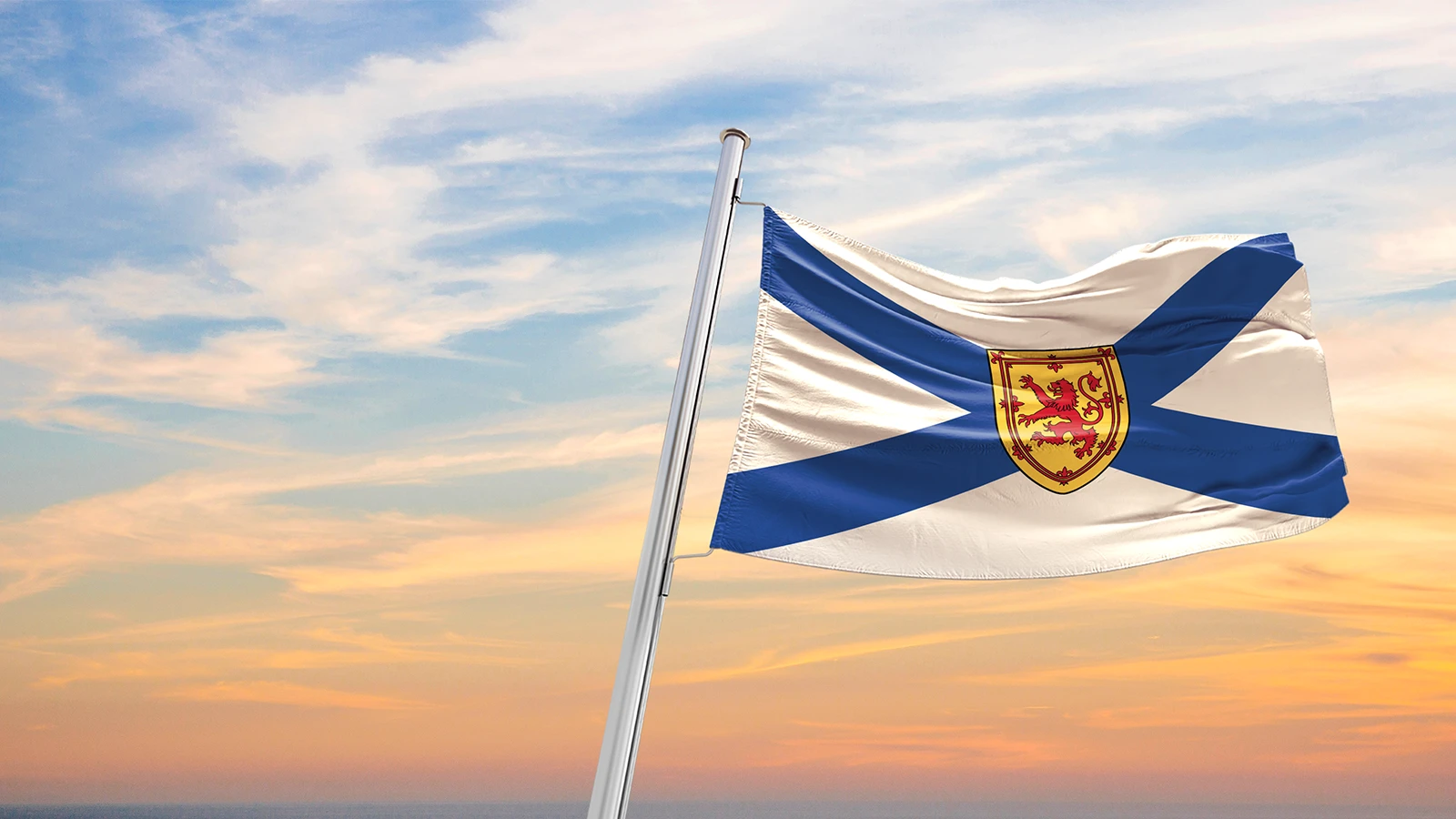 Nova Scotia flag flying on a pole with a lightly clouded blue sky background