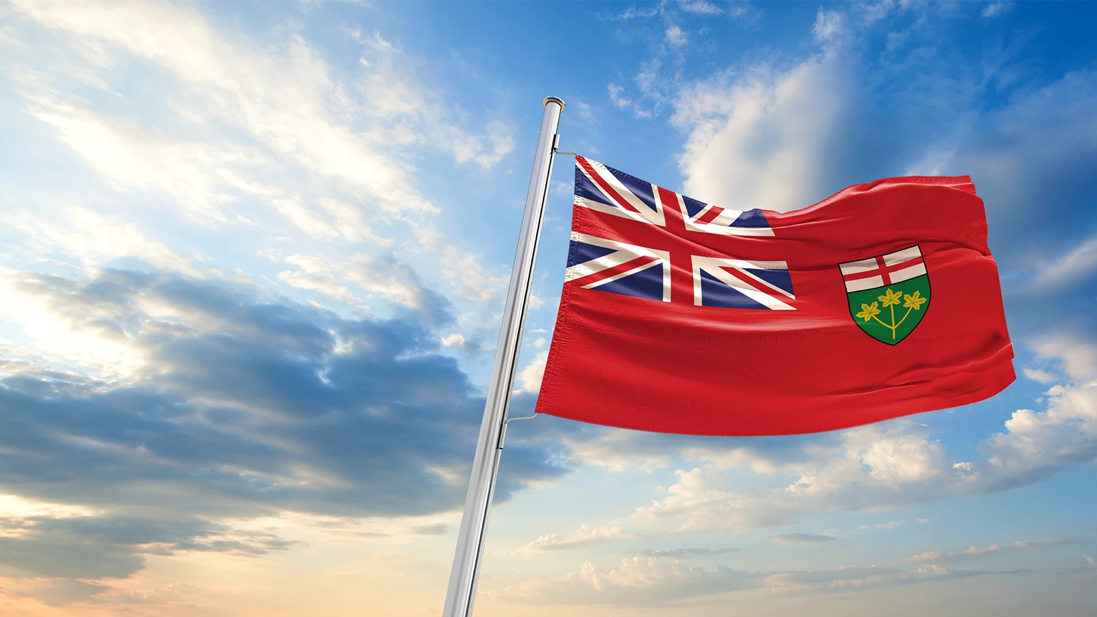 Ontario flag flying high above a blue sky