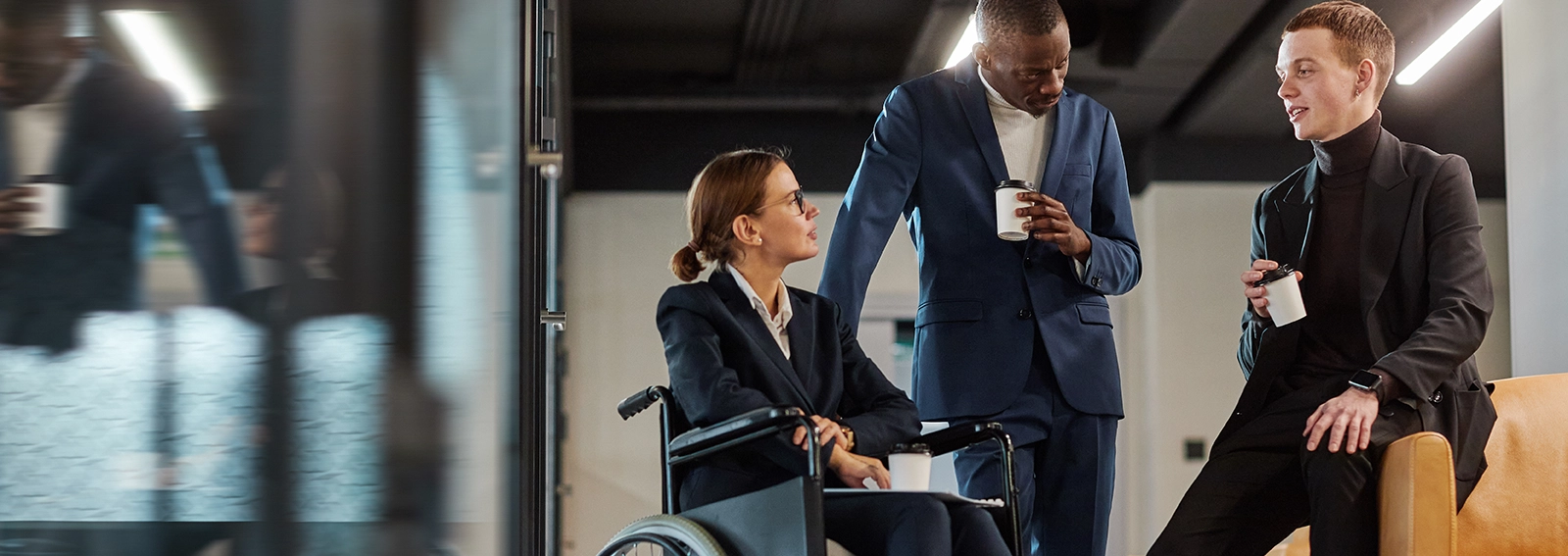 Two workers, one in a wheelchair, talking together in an office.