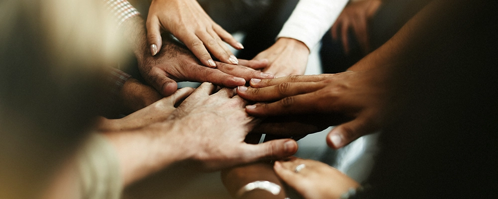 Group of people putting their hands together.