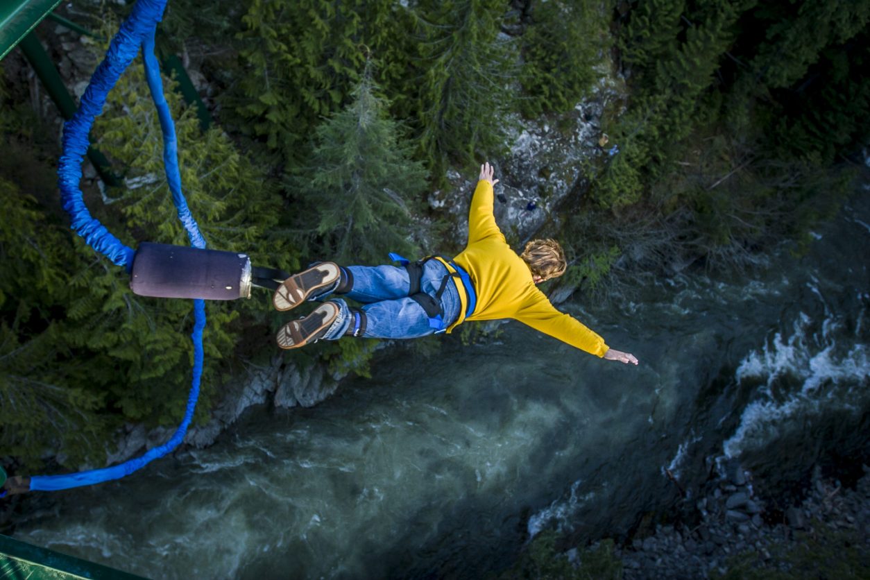person bungee jumping over a creek