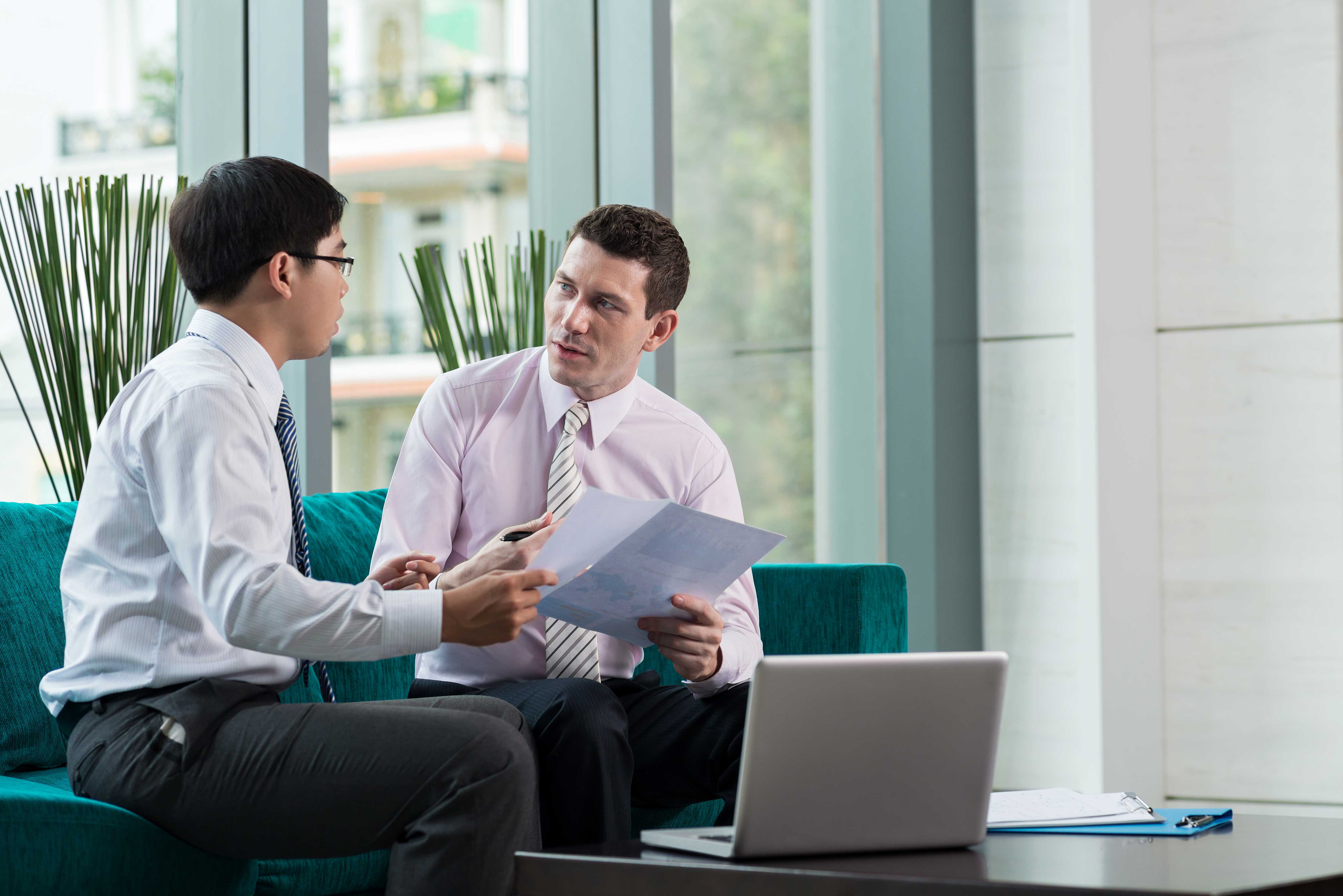 two people sitting having a discussion with a laptop in front of them