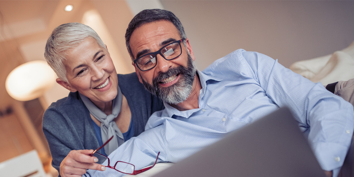A man and a woman looking into a laptop screen.