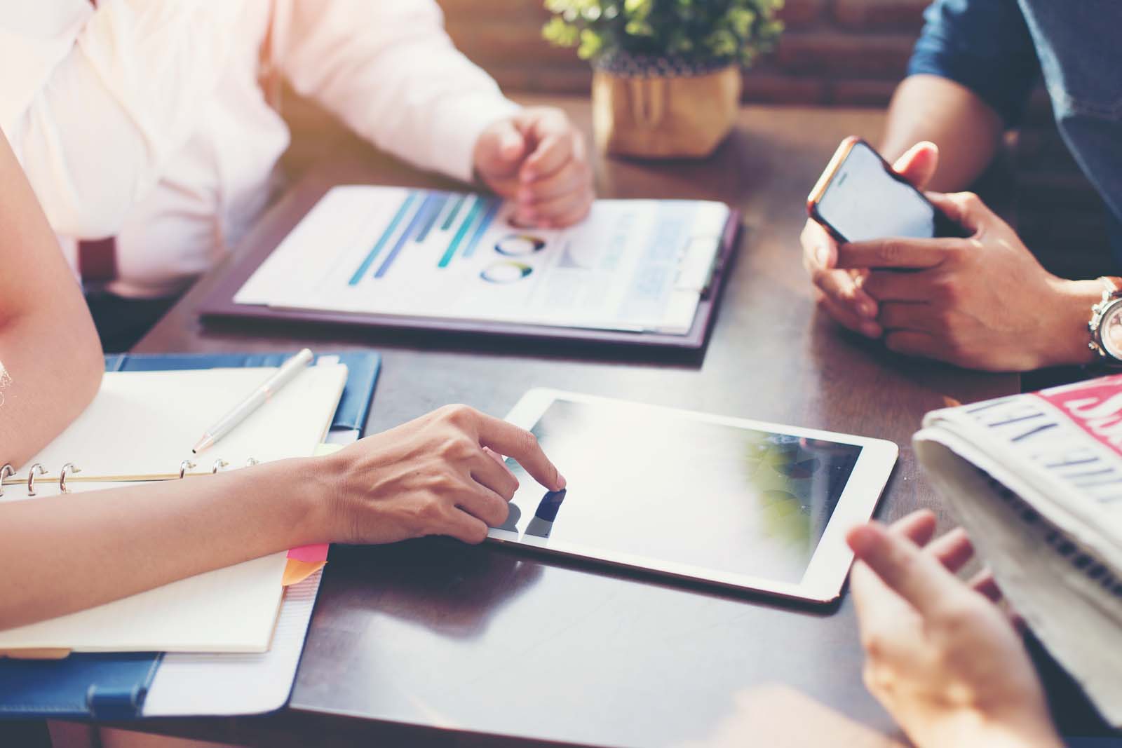 four people in a meeting consulting information on a tablet