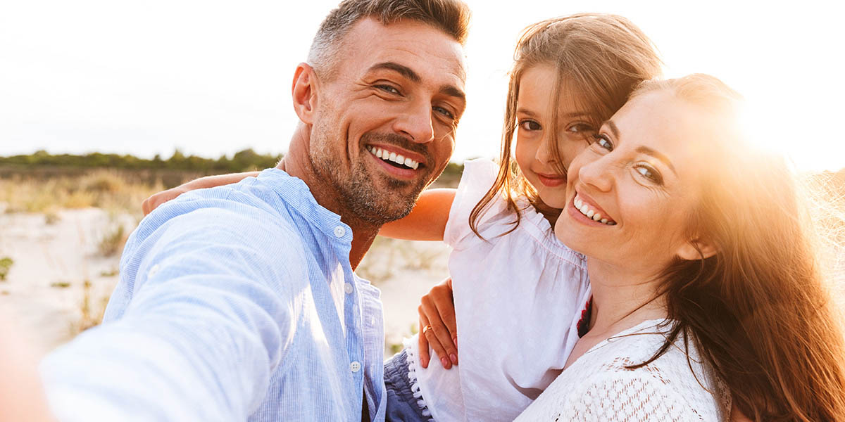 a husband wife and daughter smiling