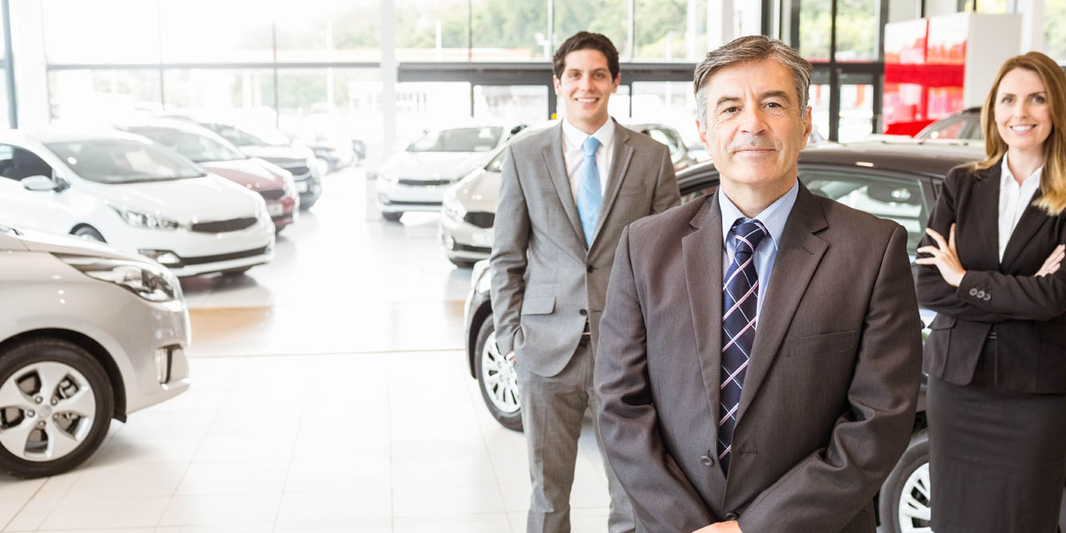 dealership employees standing by cars parked inside