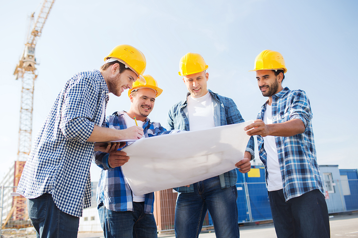 construction workers in hardhats reviewing blueprints