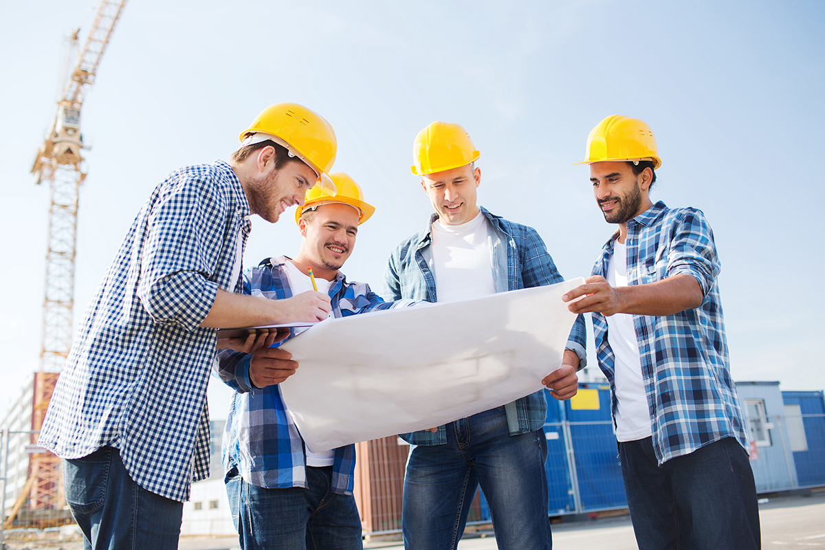 construction workers in hardhats reviewing blueprints