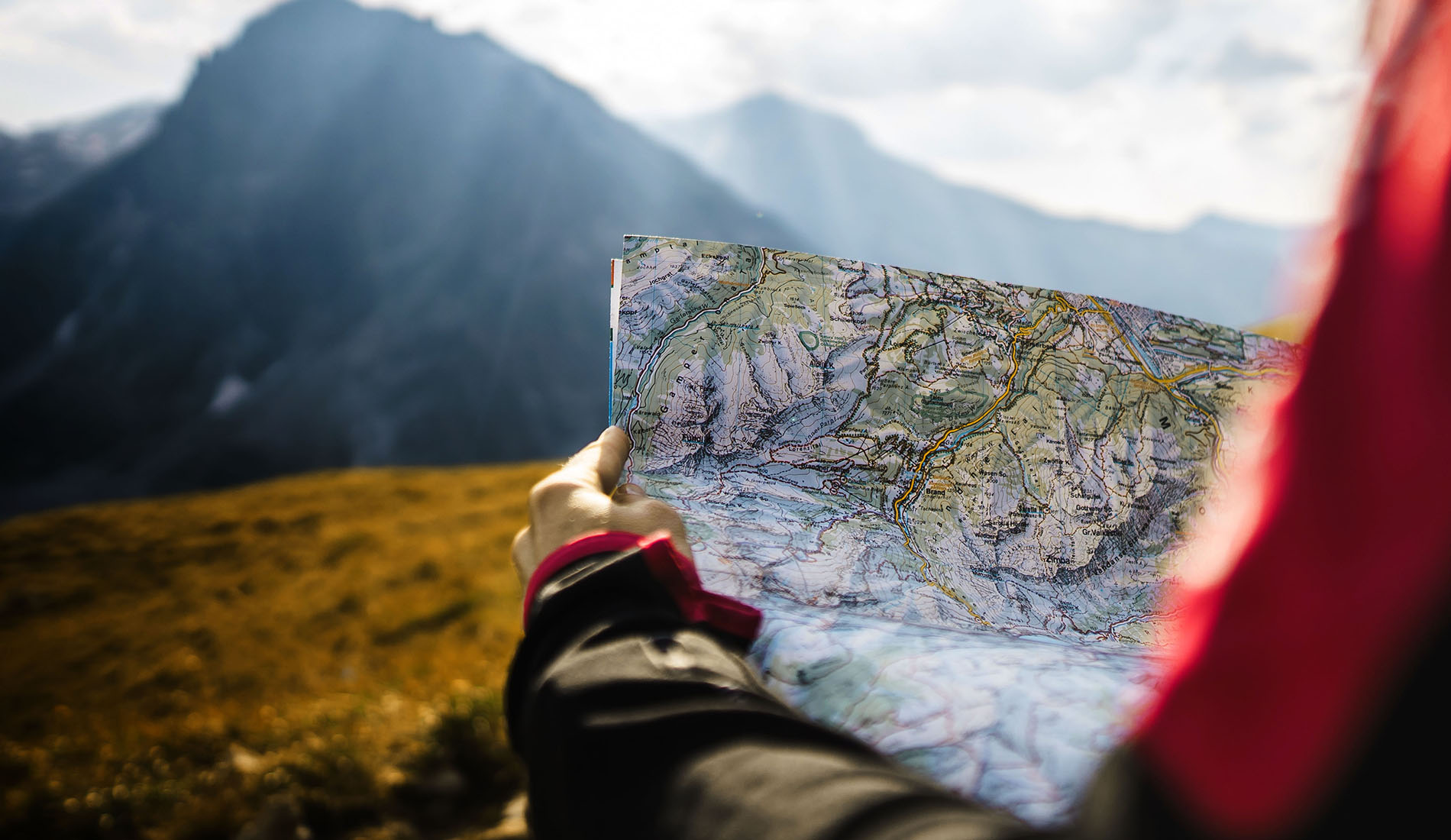 Person standing on a mountain looking at a map