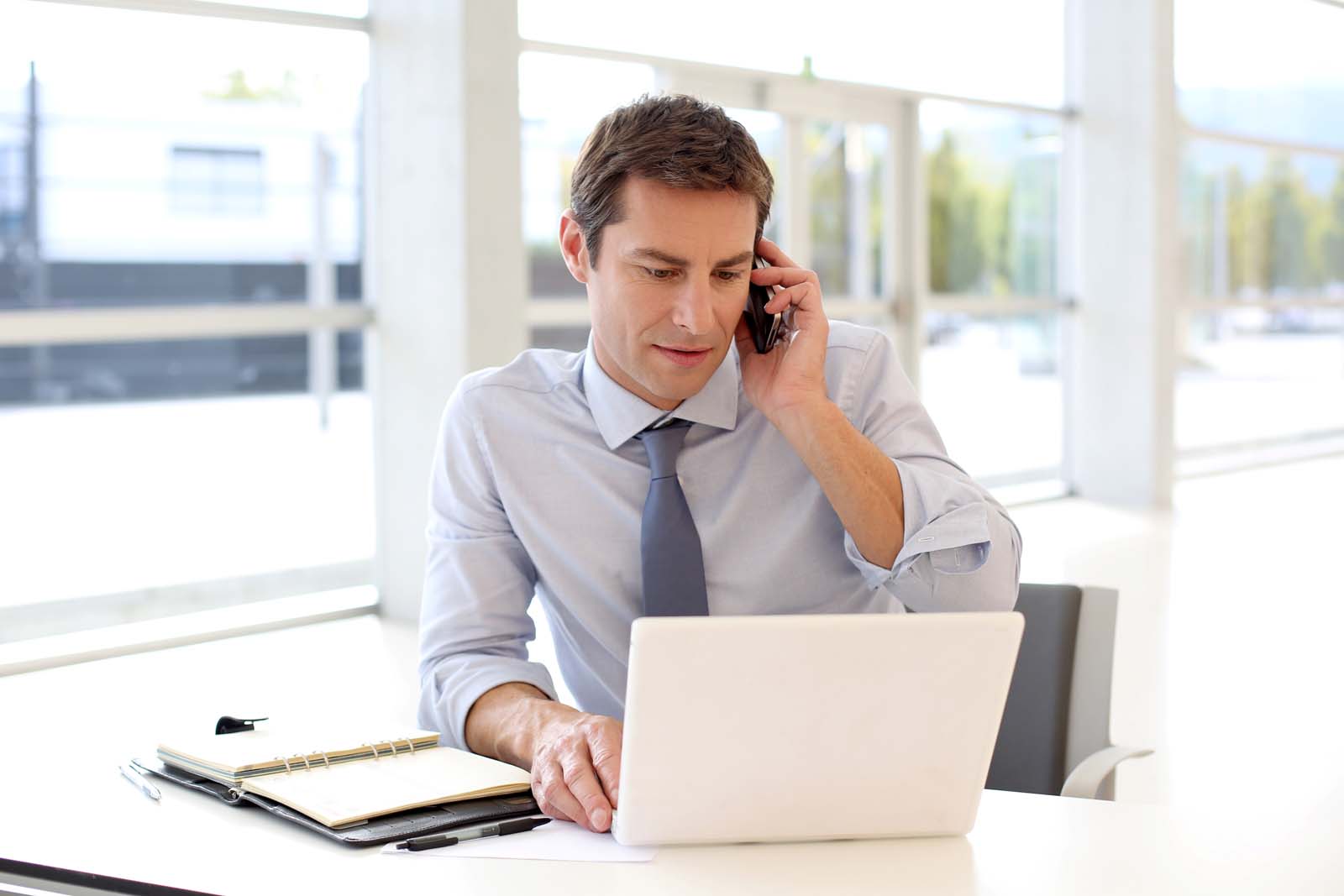 person on the phone and working on a laptop