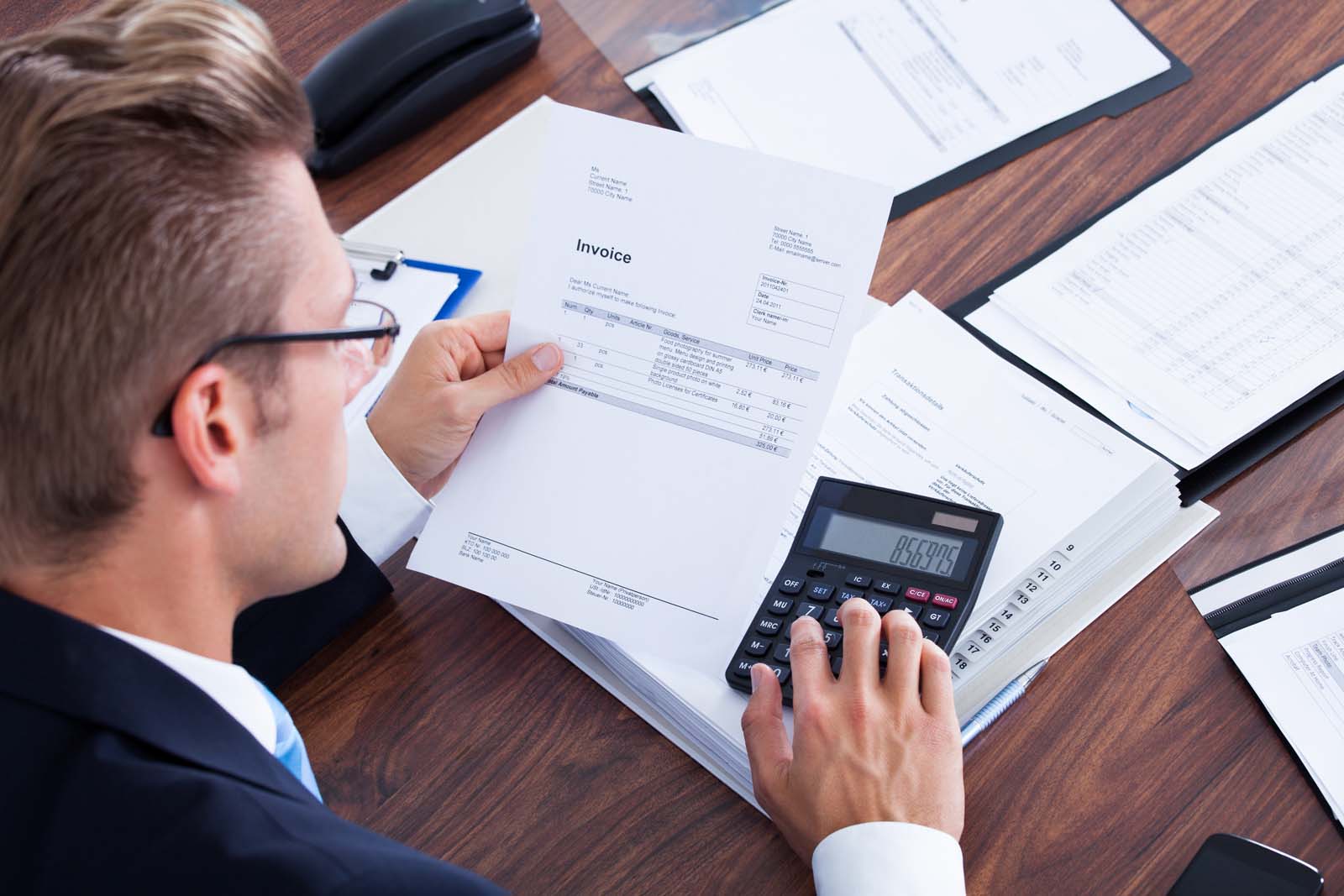 person working on documents using a calculator