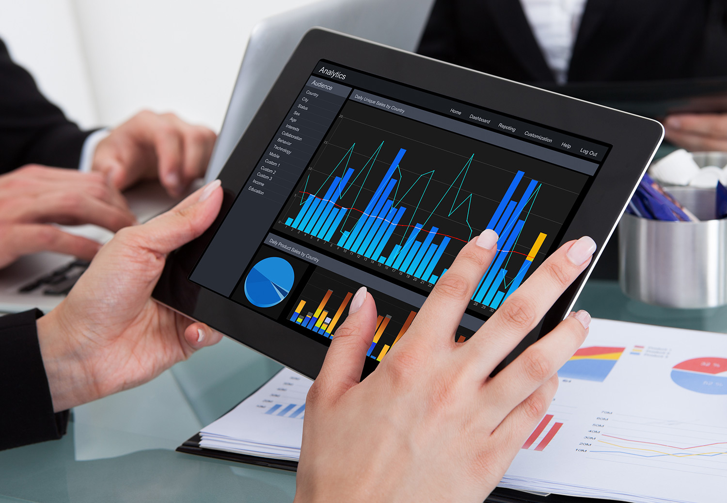 person looking at a tablet with graphs on the screen