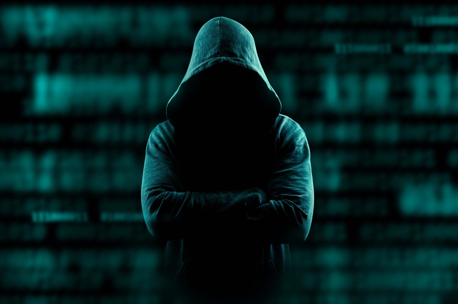 ominous person standing in the dark wearing a hood