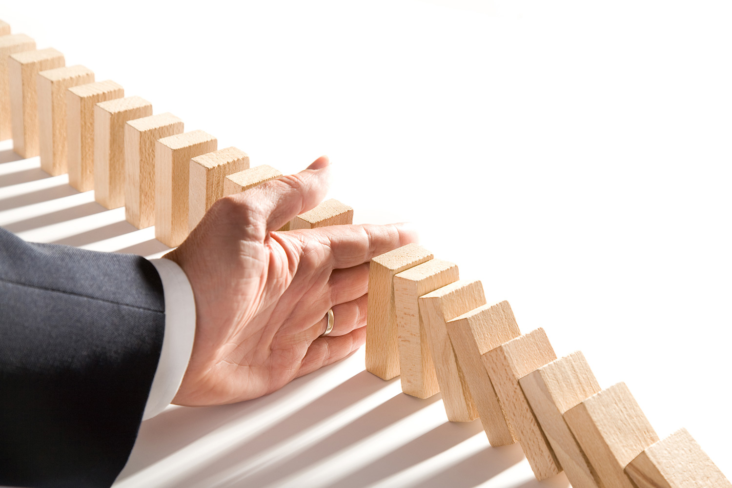 someones hand blocking dominos from falling