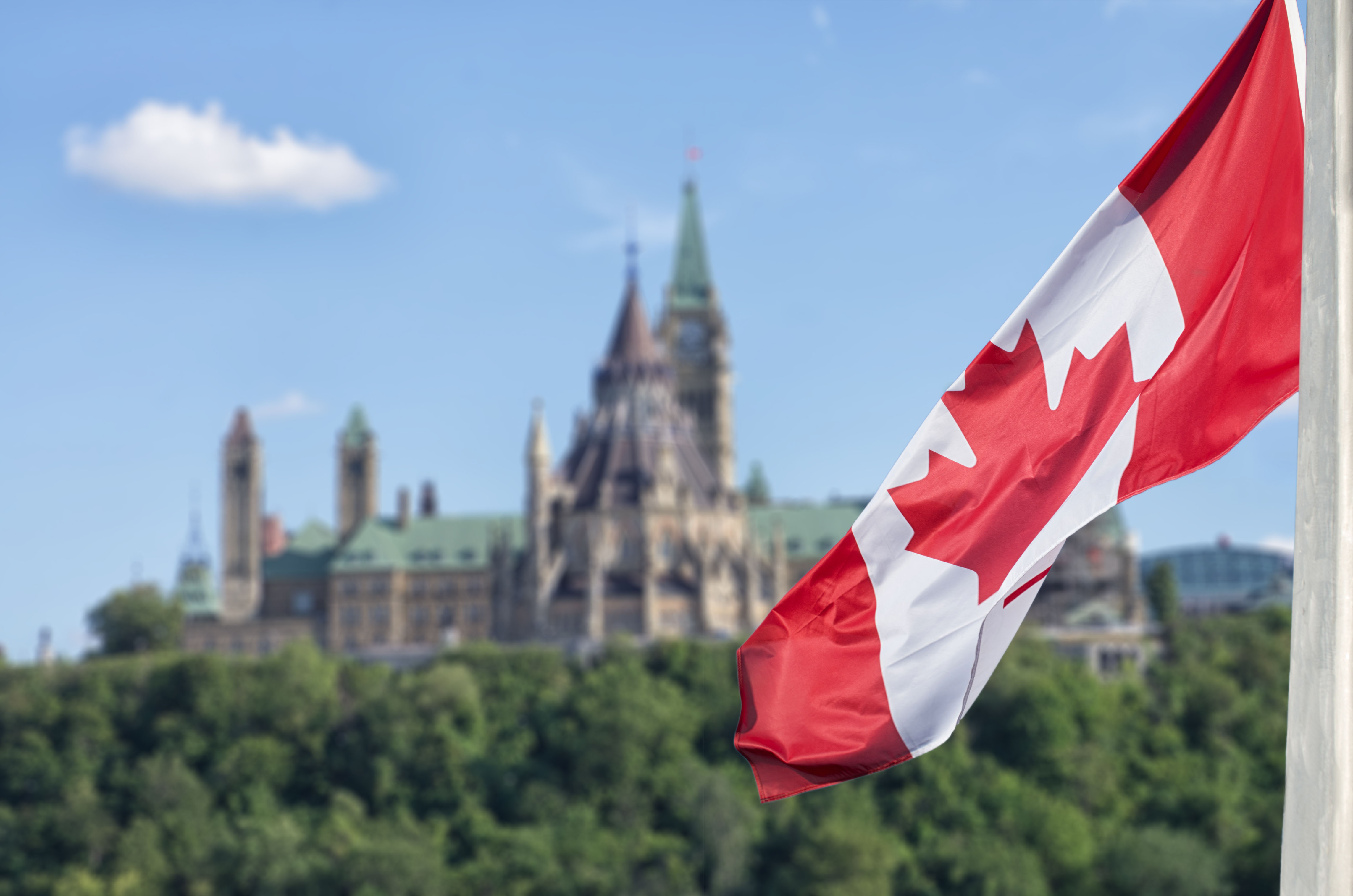 Canadian flag flying in front of the Canadian Parliament building