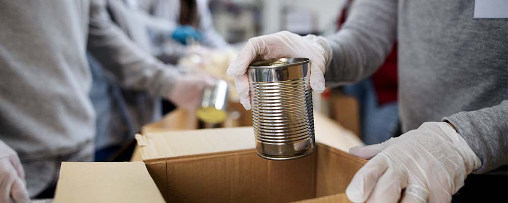 People putting canned goods into box