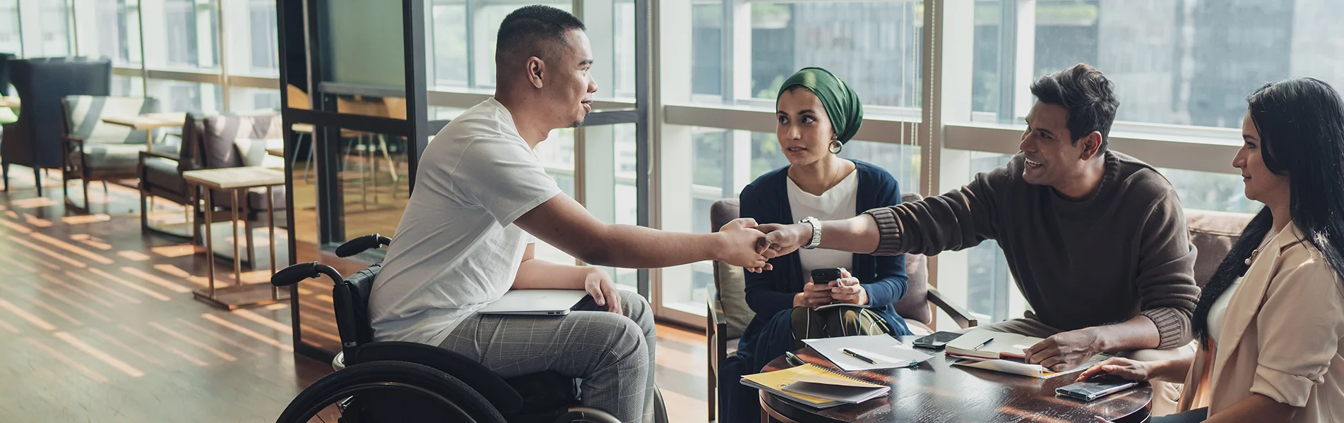 Groupe diversifié de personnes souriantes et parlant entre elles sur le lieu de travail.