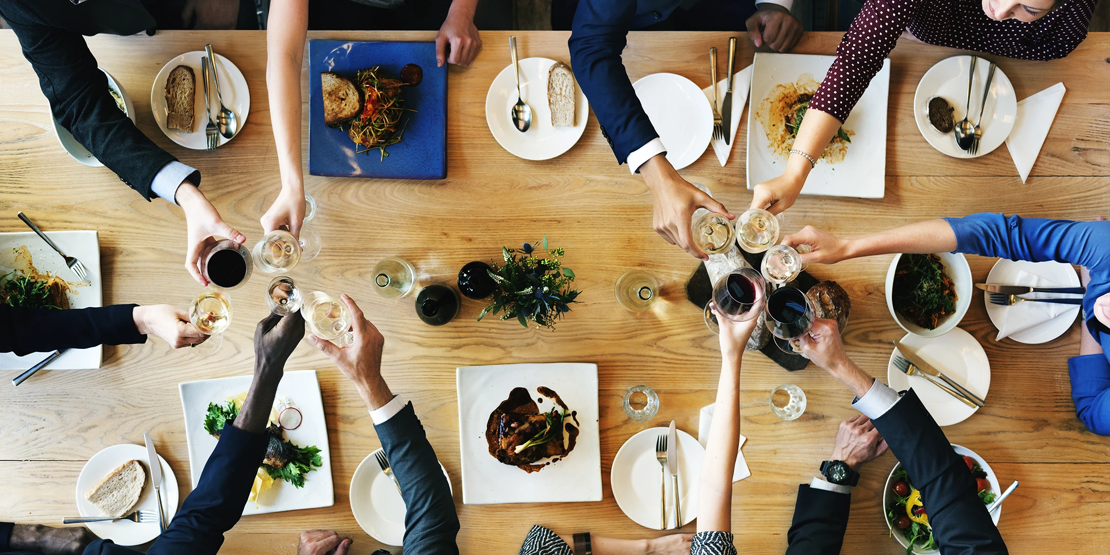 A group of people enjoying a meal together, raising wine glasses in celebration and conversation.