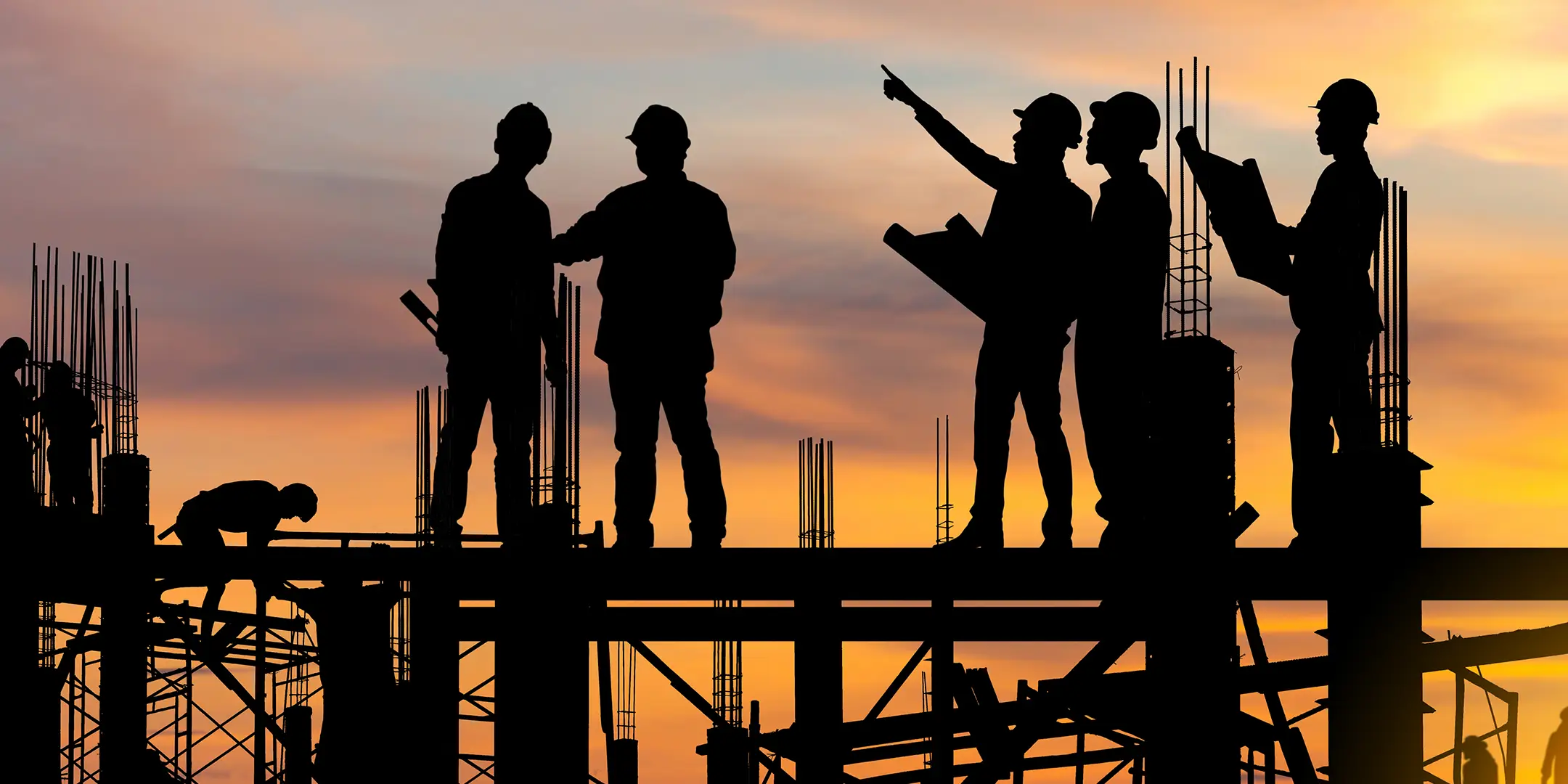 Silhouette of workers on building site construction site at sunset in evening time