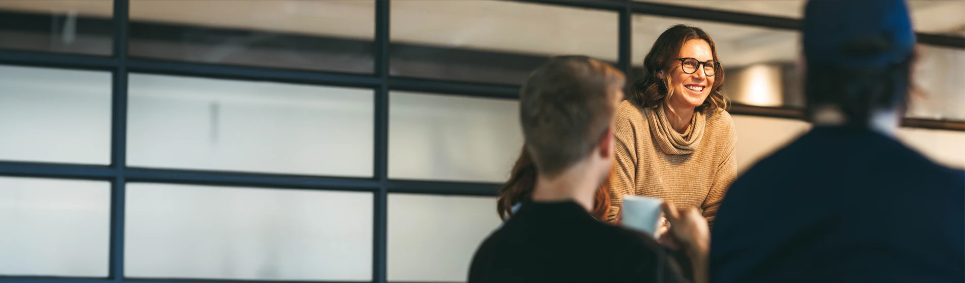 Focus with a blurry background of a woman smiling amongst her coworkers.