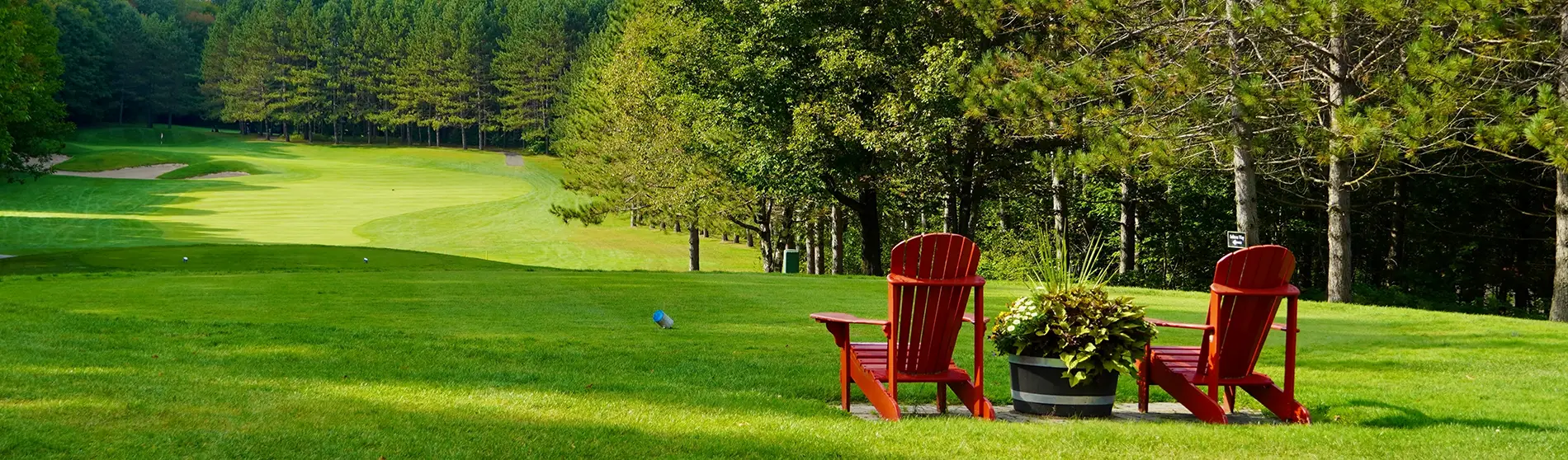 Two Adirondack chairs overlooking green lawn in a beautiful golf course.