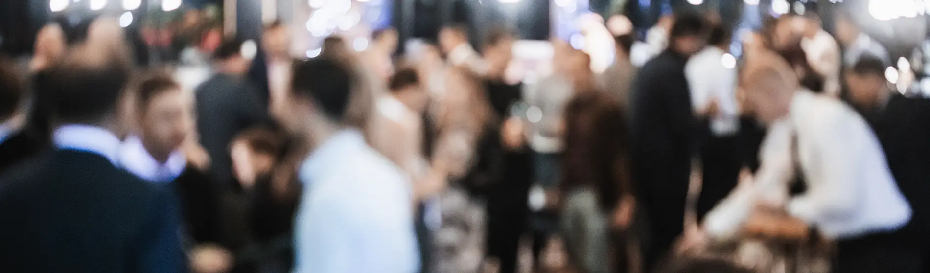 Blurred photo of a group of people at a conference.