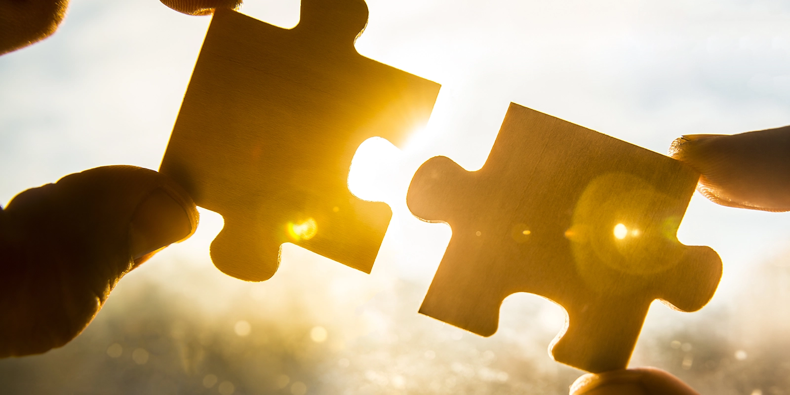 hands going to connect two puzzle pieces with light in background