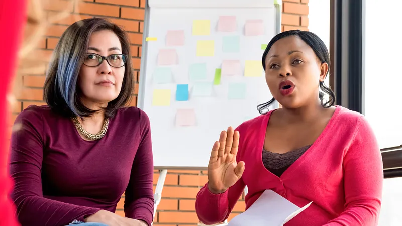 Deux femmes discutant devant un tableau blanc