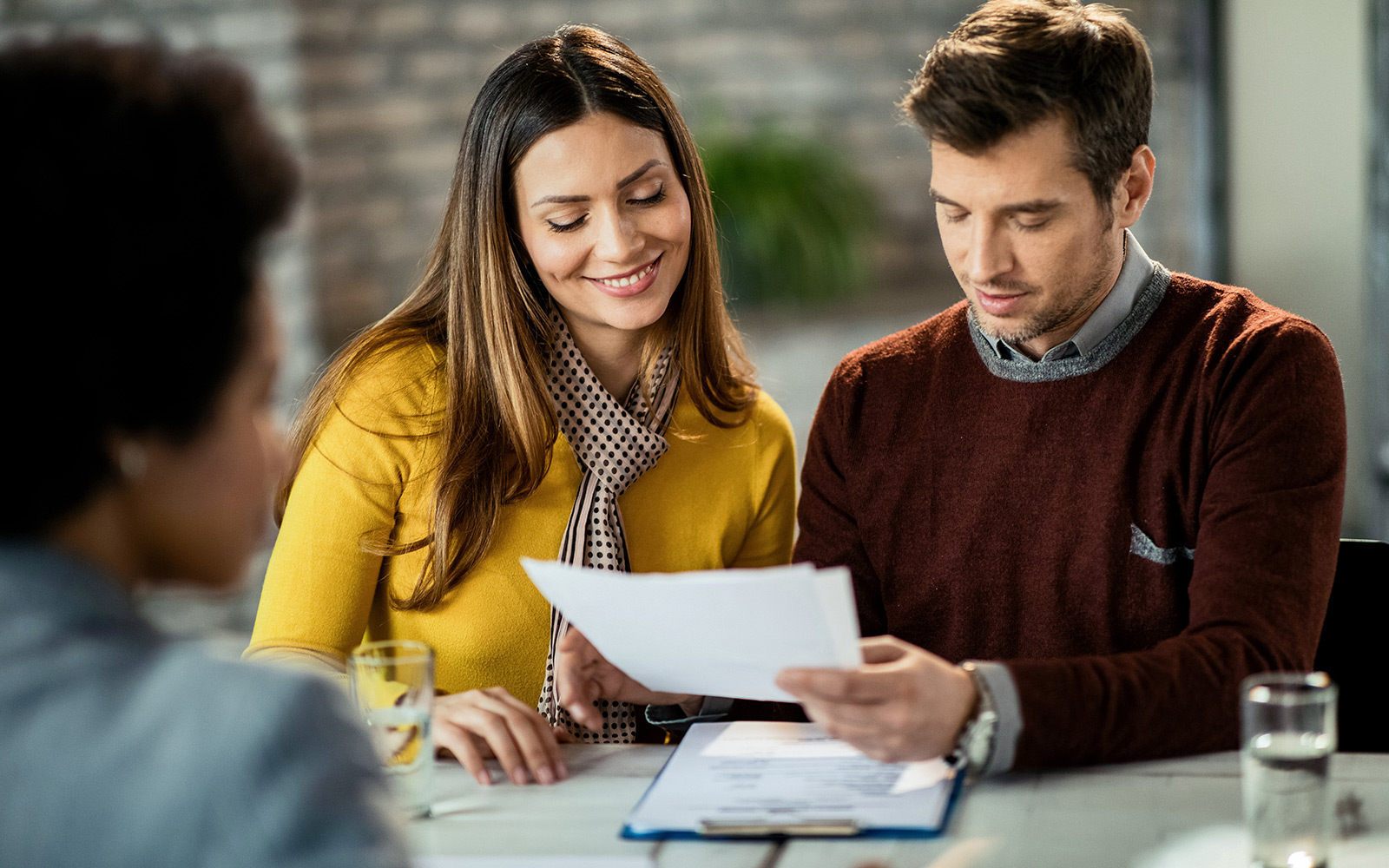 Happy couple going through paperwork and analyzing a contract in a meeting with credit union