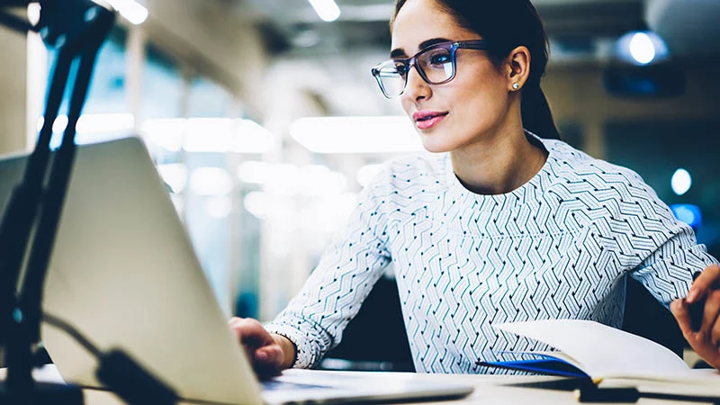 A woman working on her laptop and notebook