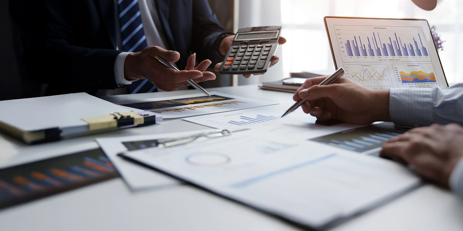 A group of business professionals are gathered around a table analyzing financial charts and graphs