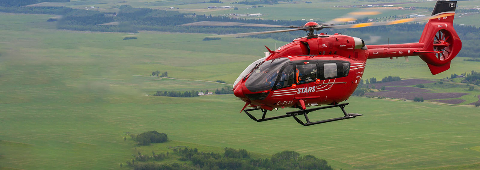 Stars Air Ambulance flying over a field