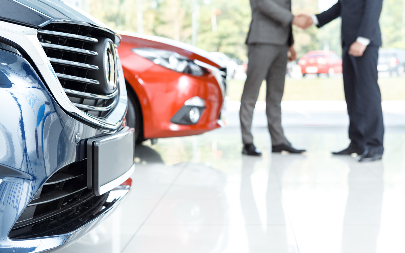 Well dressed men discuss their dealerships insurance needs as well as the spectacular polish of their showroom floor