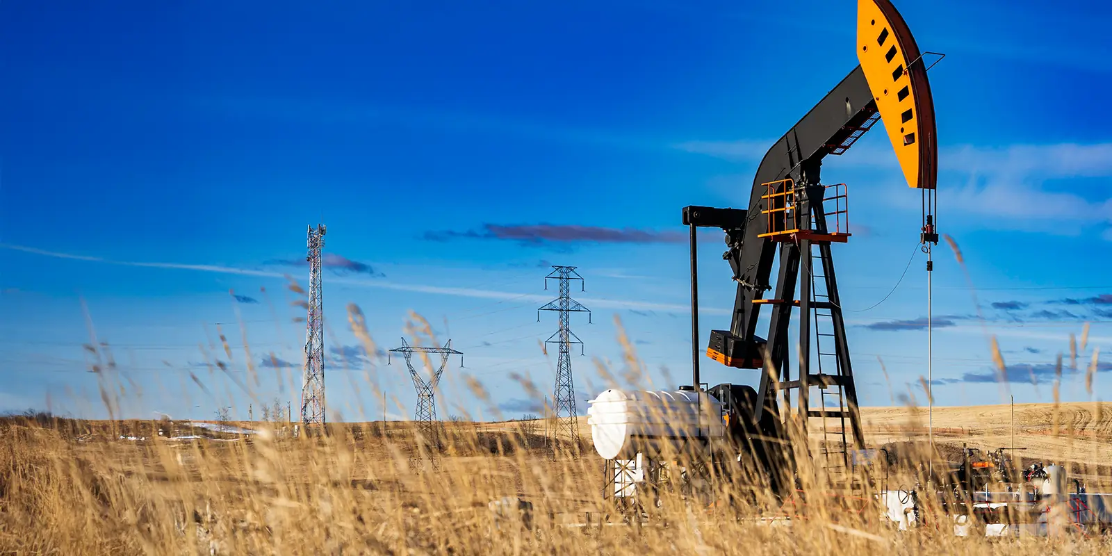 An oil pump jack working on an agriculture field with oil and gas equipment