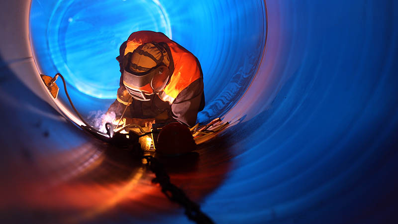 Travailleur de l'industrie soudant à l'intérieur d'un tuyau de pétrole et de gaz