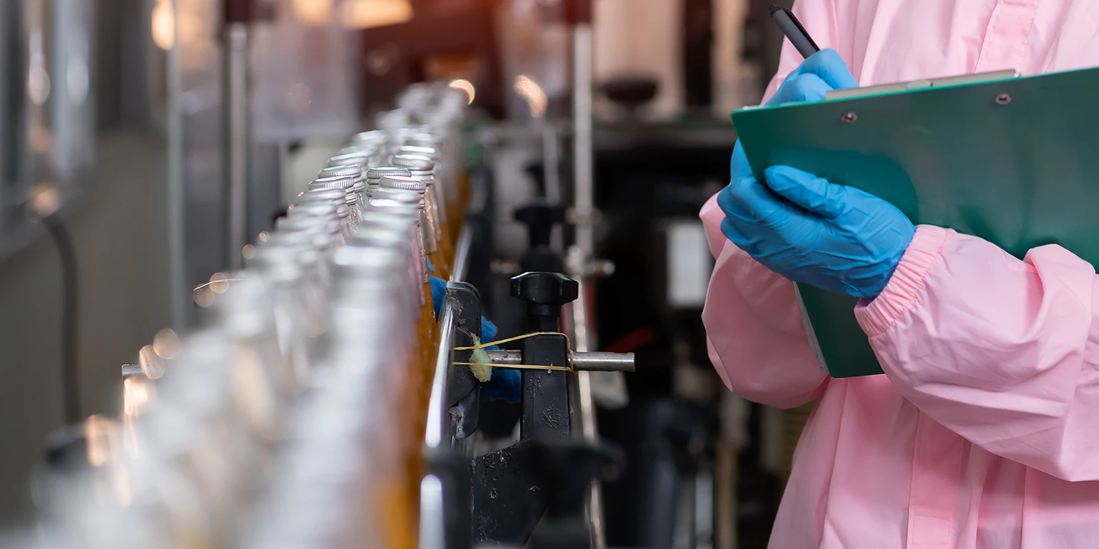 female food production worker looking at production line holding clip board