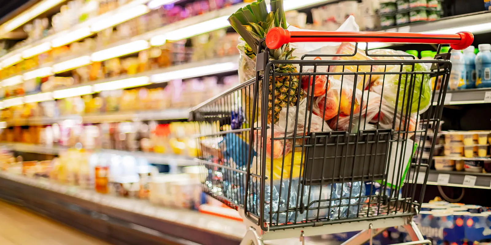Un chariot d'épicerie rempli de produits d'épicerie dans une allée d'épicerie