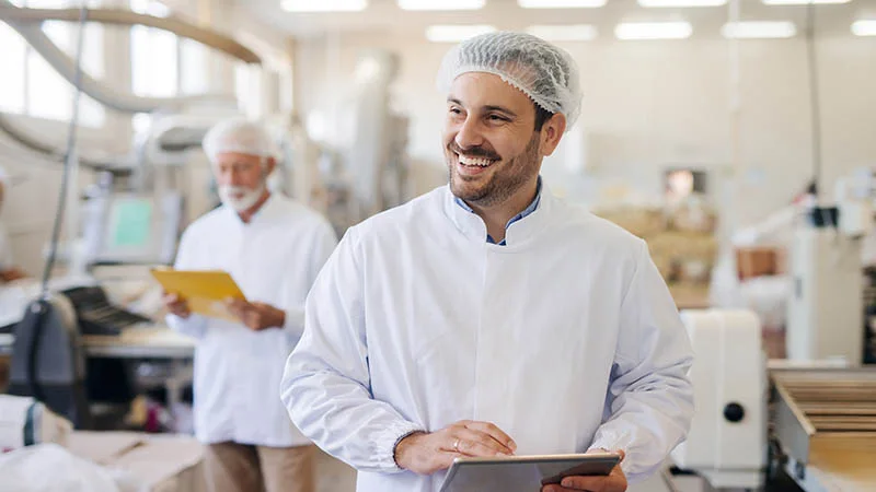 Two men wearing hairnets in a factory