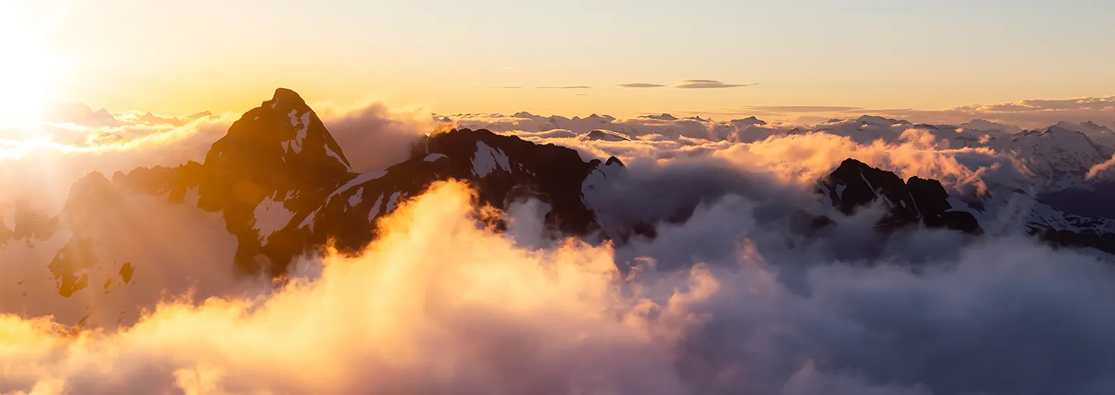 Mountain peaking through the clouds in a sunrise
