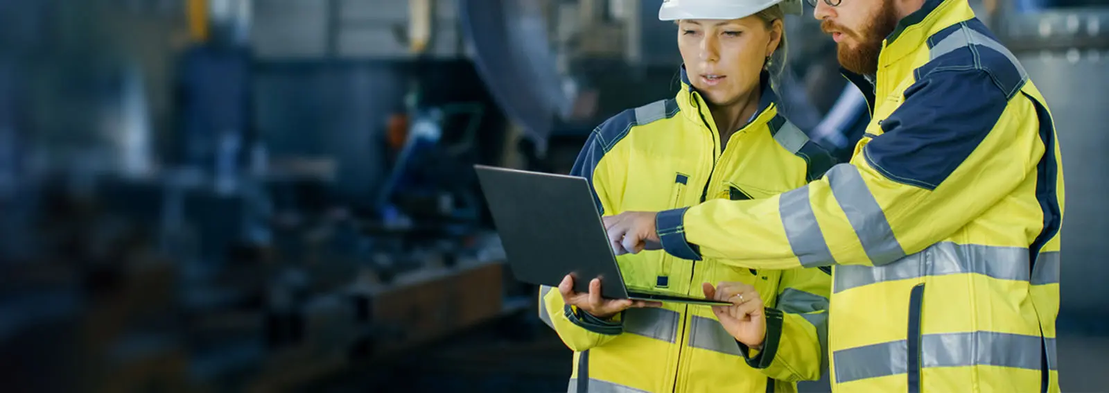 Two manufacturing workers looking at a laptop together.