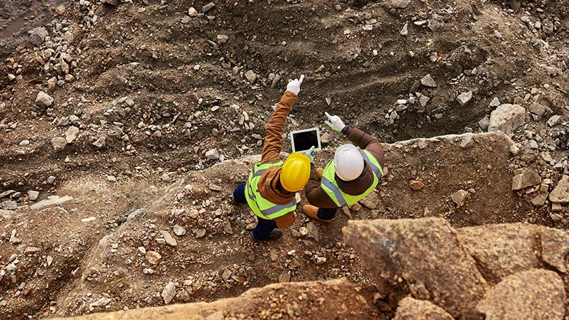 Une vue aérienne de deux travailleurs portant des casques et des gilets de sécurité sur un site minier