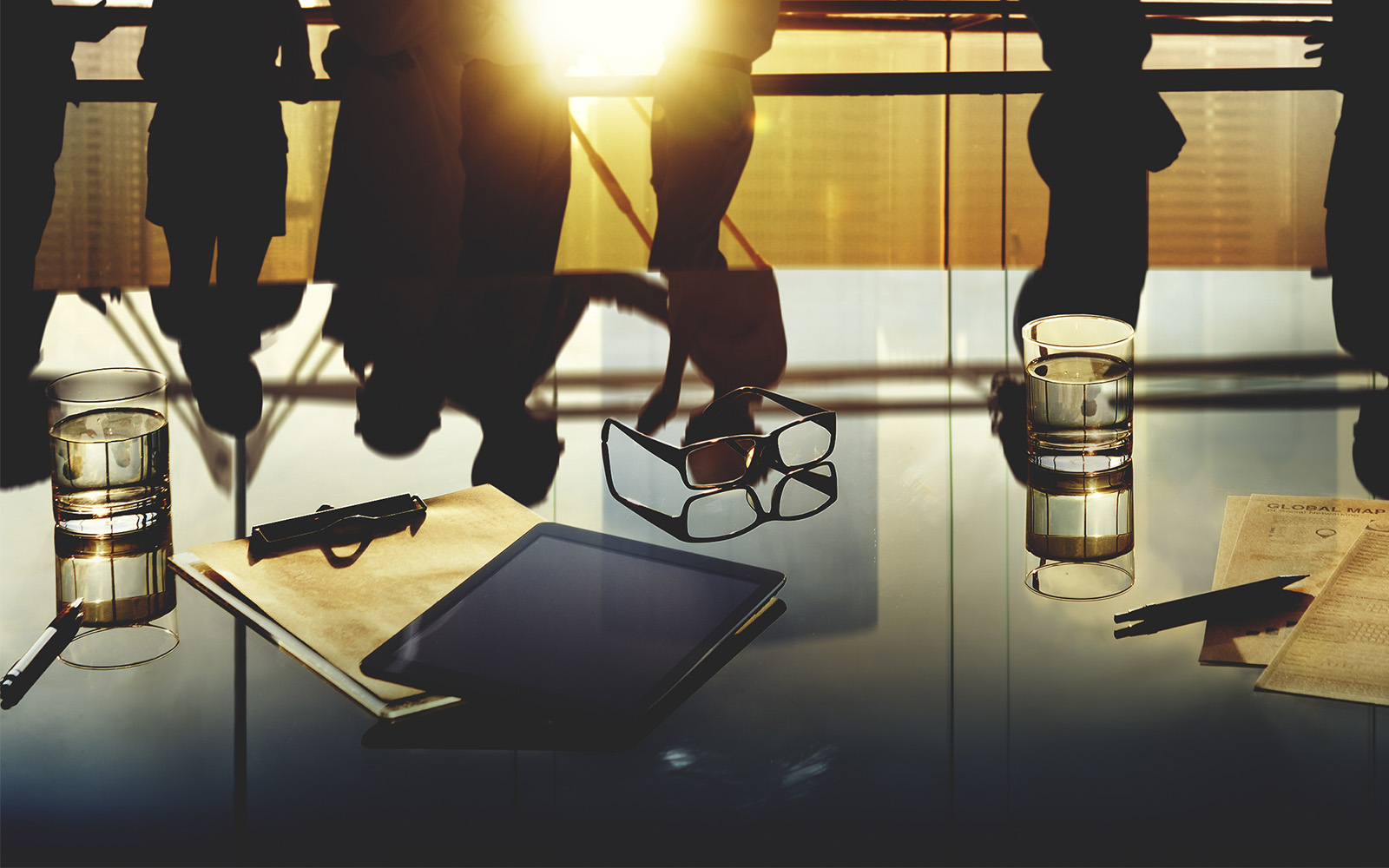 glasses and folders sitting on a glass table in business room 