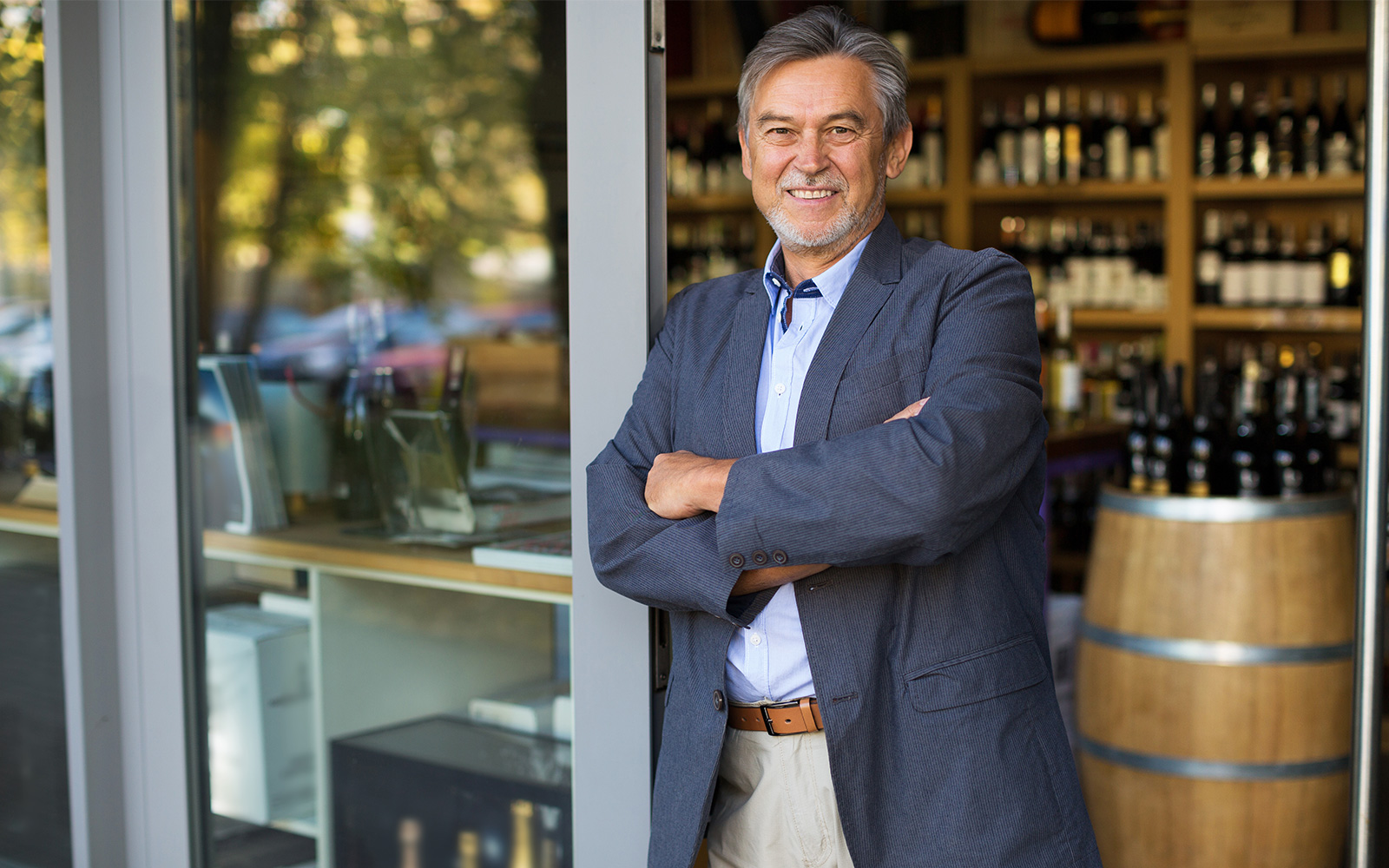 homme avec les bras croisés devant un magasin de vin