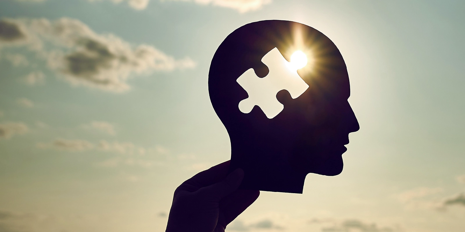 meantal health abstract cut out of head against sky and sun shining through puzzle shape