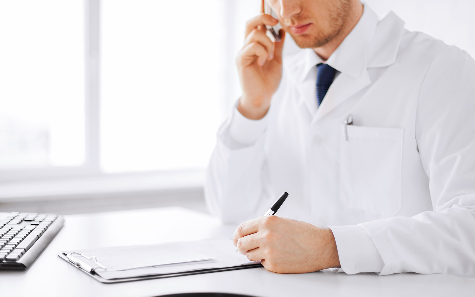 A doctor writing on a clipboard