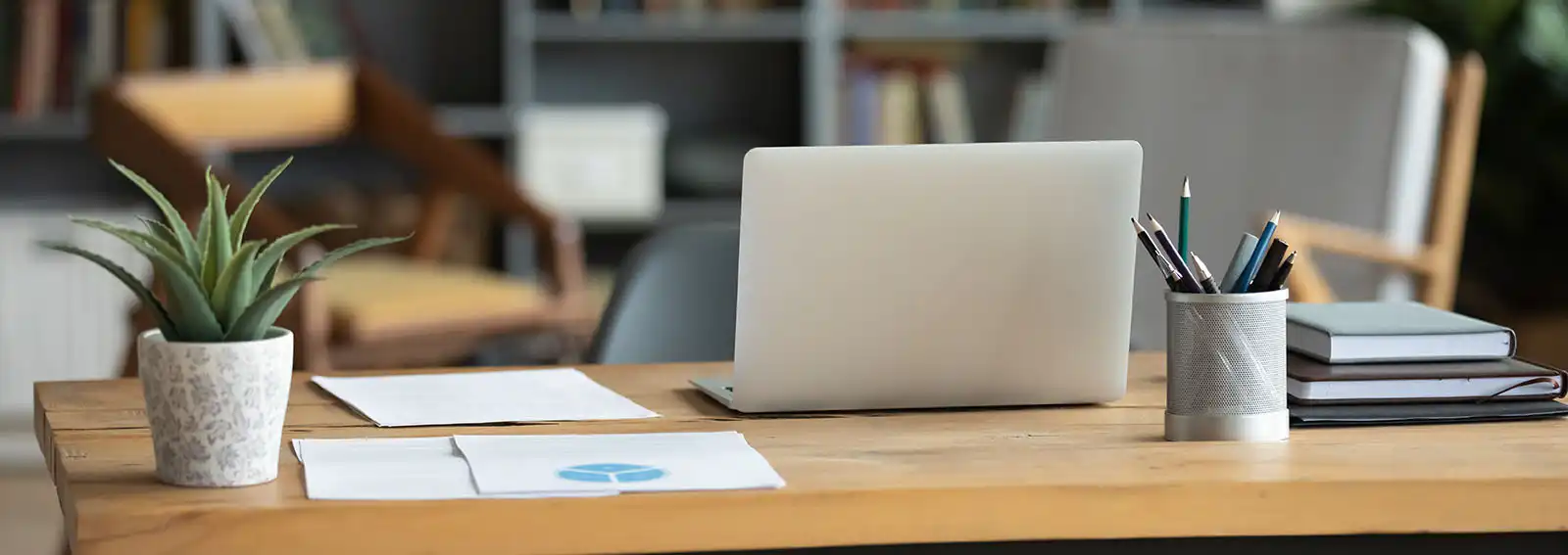 Modern office with a laptop and charts on a desk.