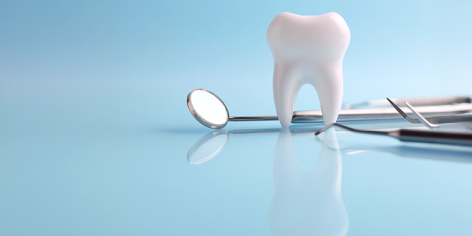 A tooth and a dental mirror with a blue background.
